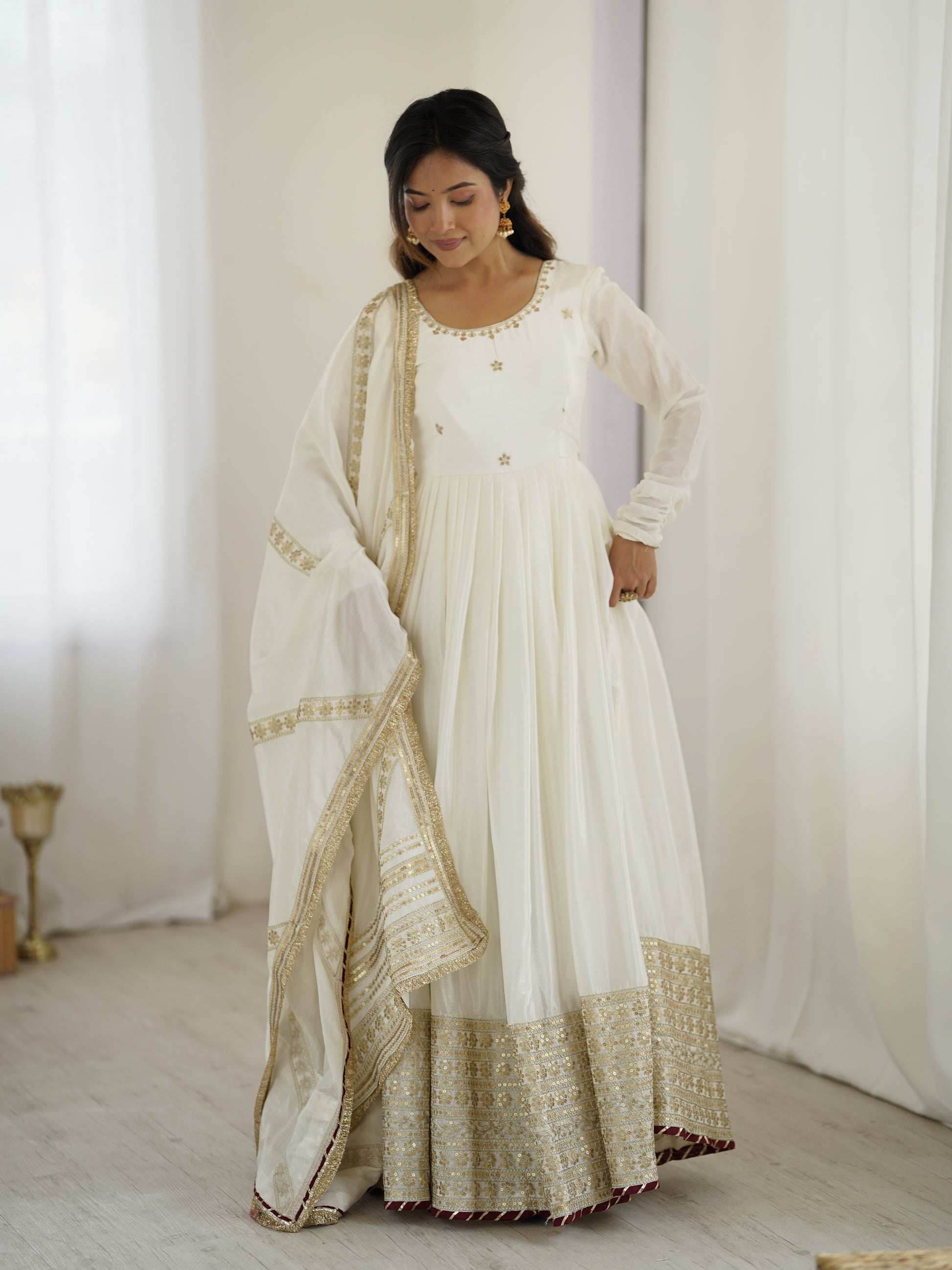 Woman wearing a white and gold traditional outfit with a plain background