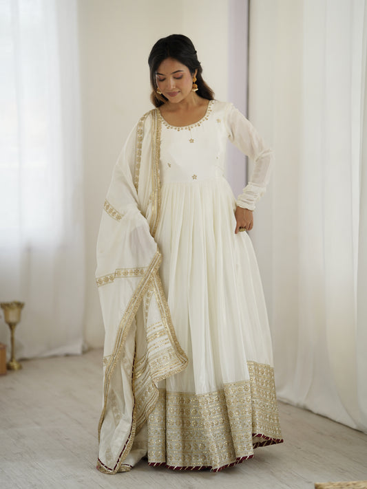 Woman wearing a white and gold traditional outfit with a plain background