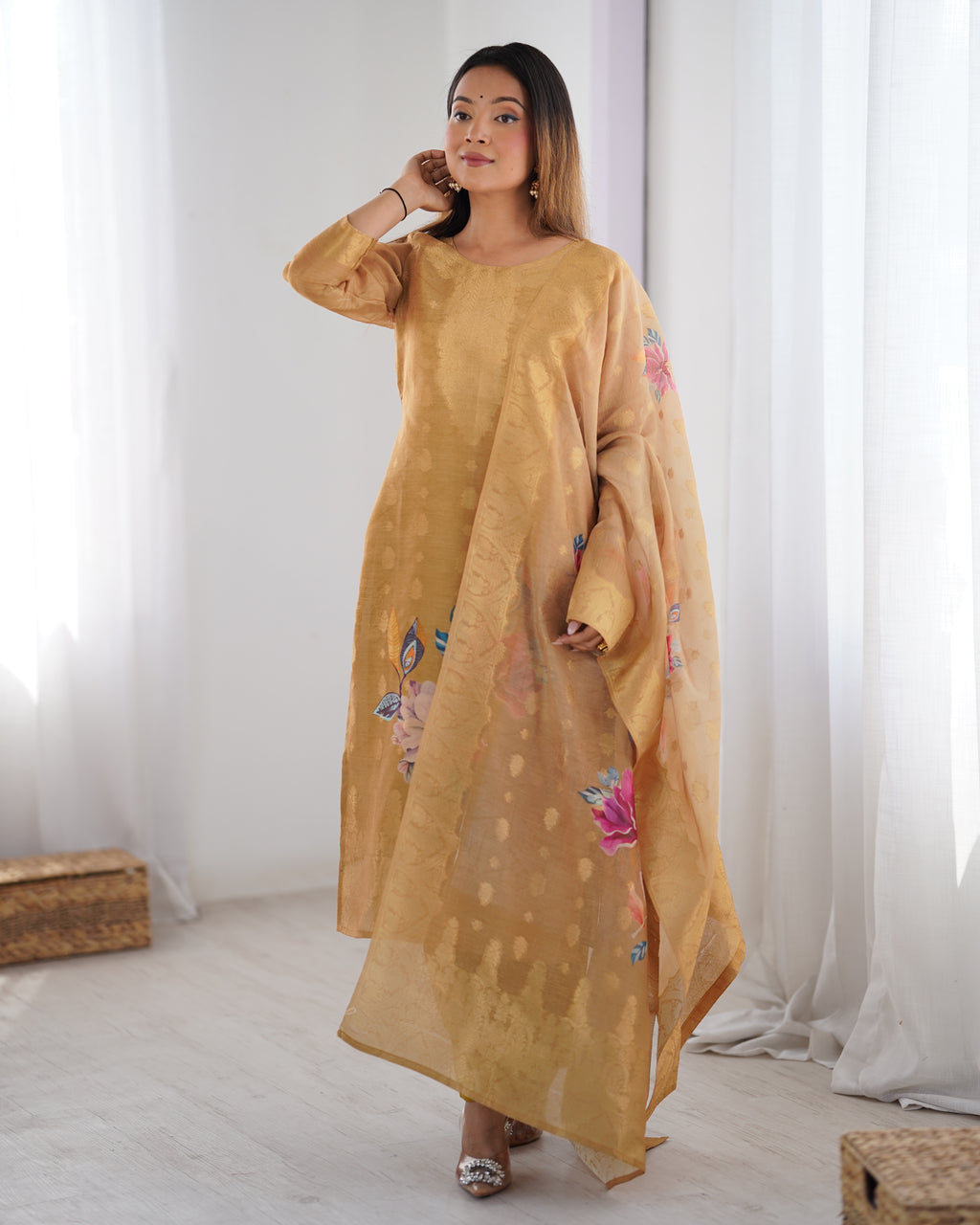 Woman wearing a mustard yellow dress with floral embroidery in a bright room.