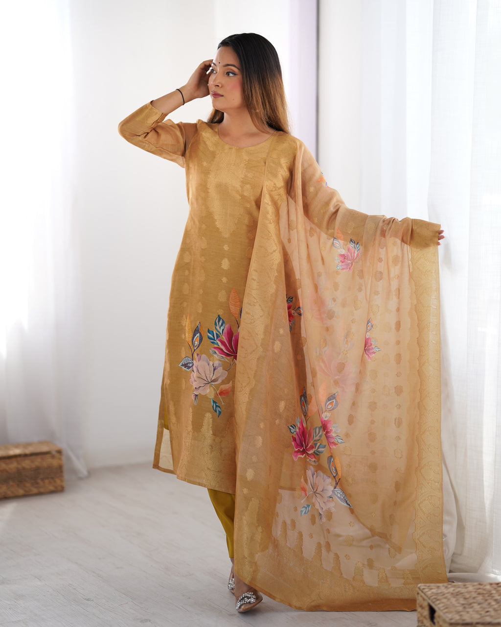 Woman wearing a mustard yellow traditional outfit with floral embroidery, holding a matching dupatta.
