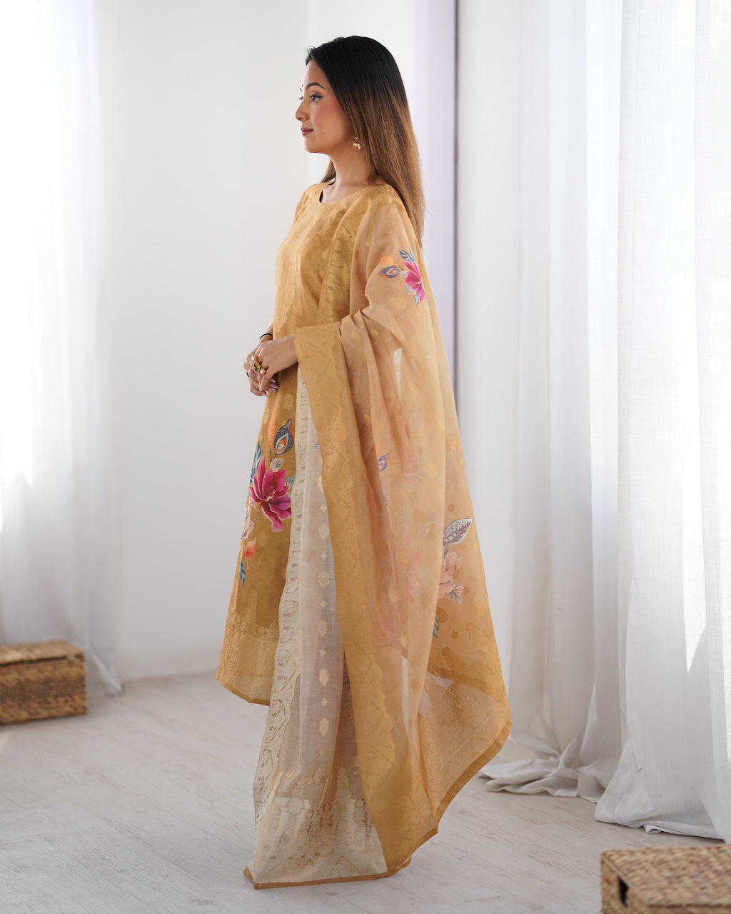Woman wearing a yellow embroidered traditional outfit in a minimalistic room.