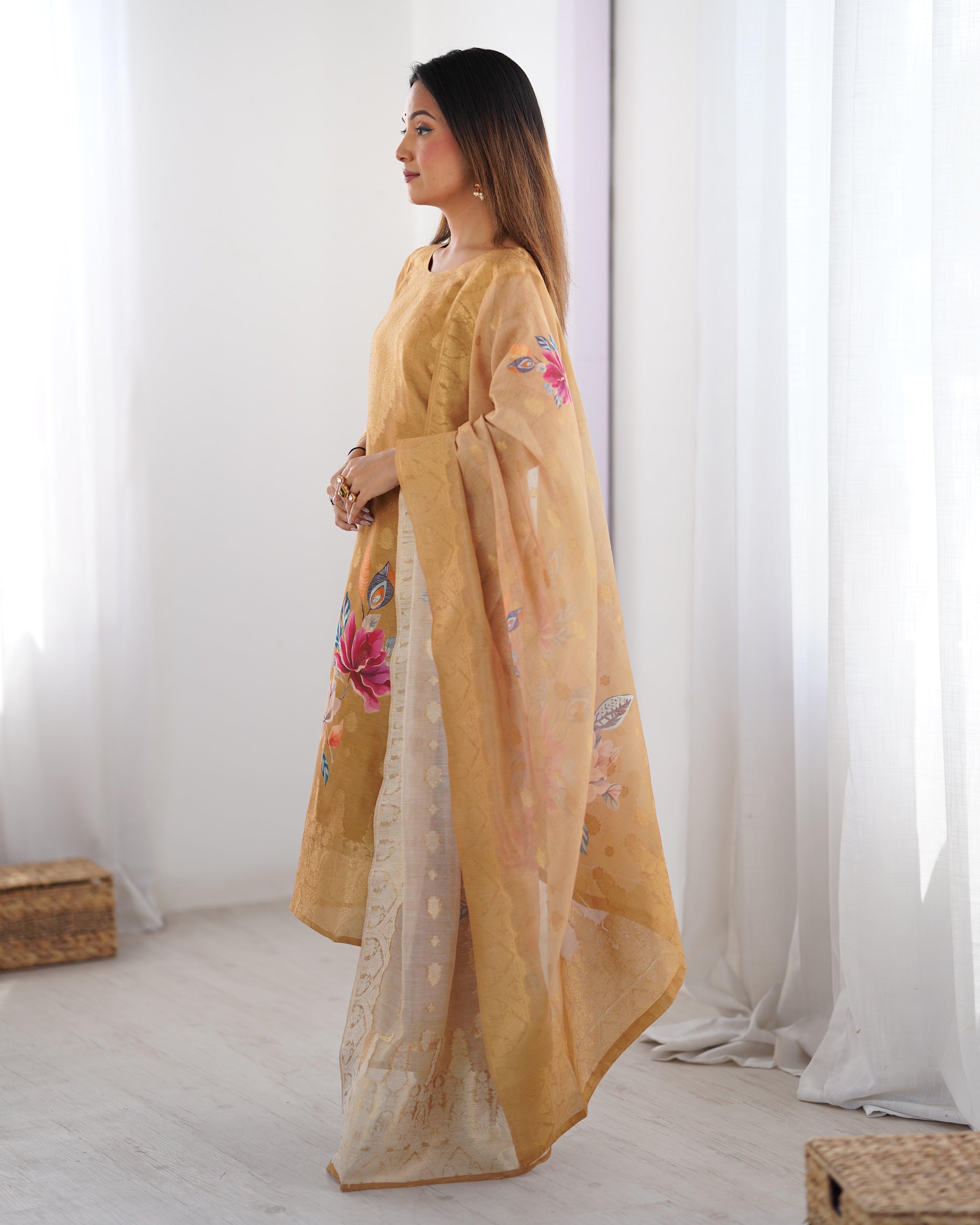 Woman wearing a yellow embroidered traditional outfit in a minimalistic room.