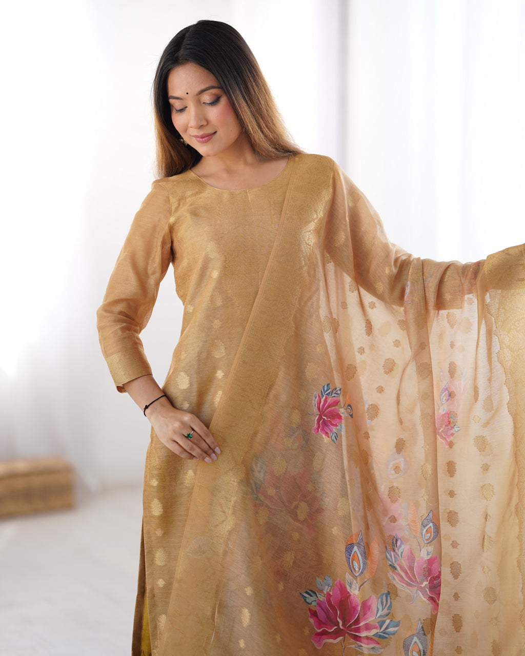 Woman wearing a beige traditional outfit with a floral dupatta against a white background