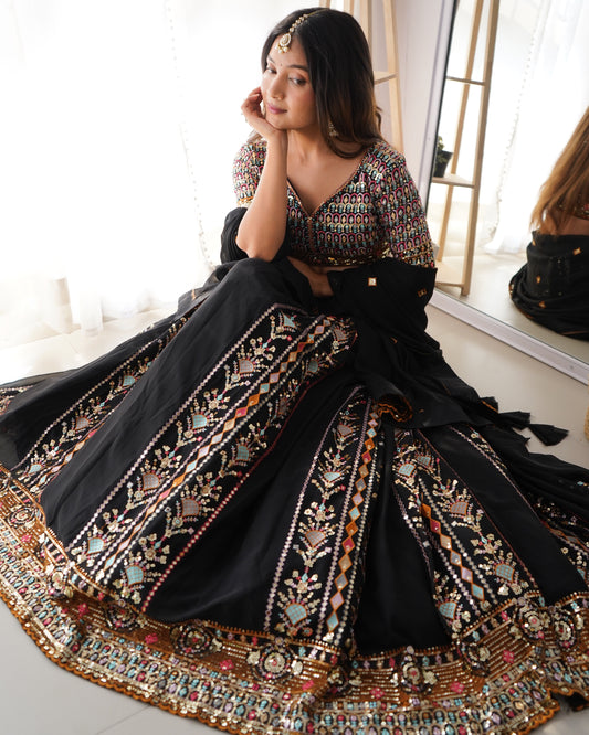 Woman wearing a traditional black and gold embroidered saree in a well-lit room.