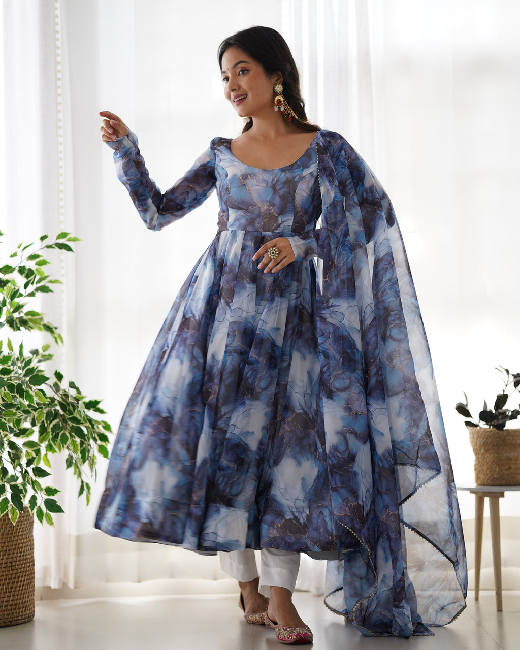 Woman wearing a blue floral dress with a matching shawl in a bright room.