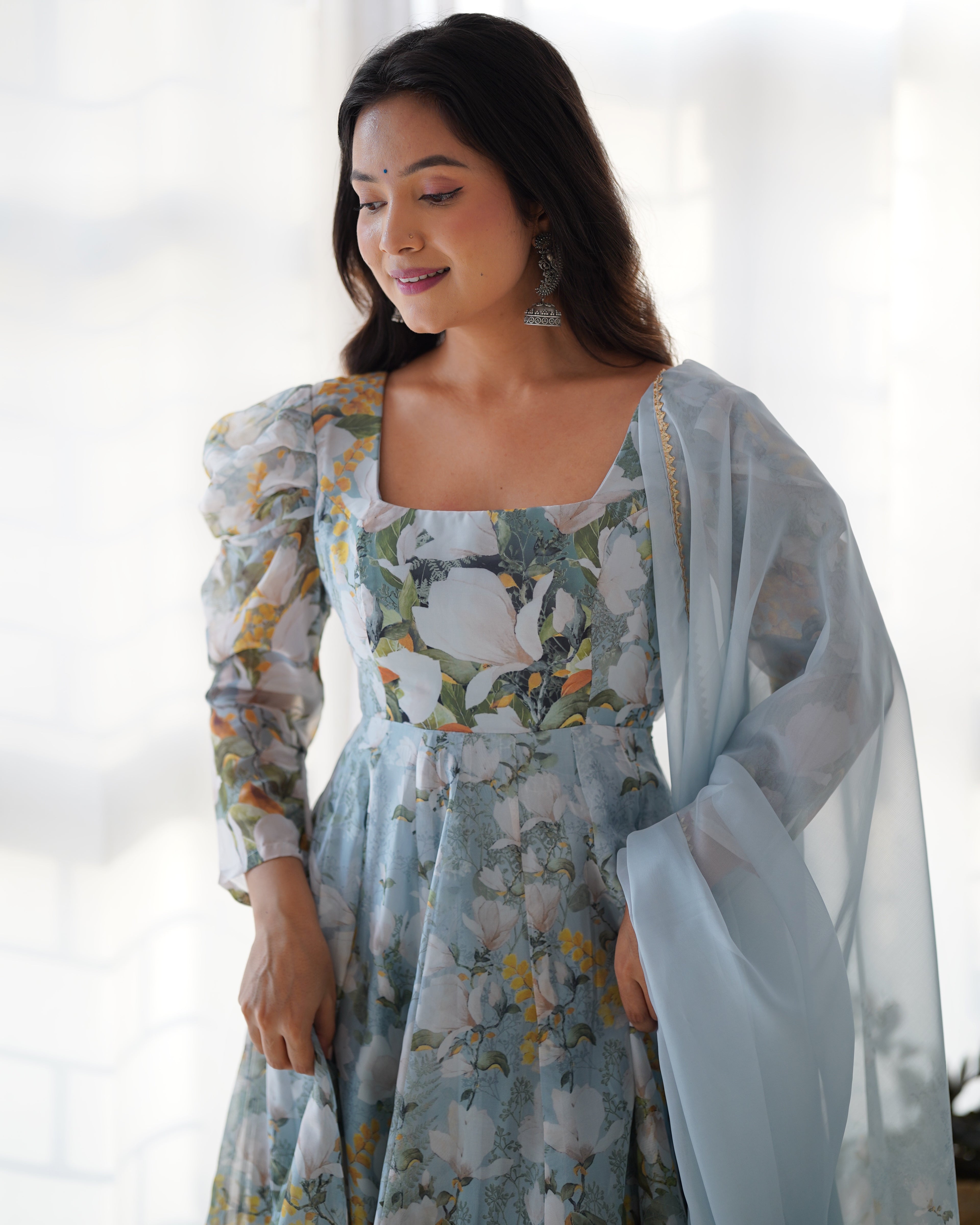 Woman wearing a floral dress with a sheer overlay against a white background