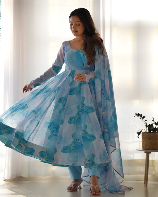 Woman wearing a blue floral dress in a bright room with white curtains.