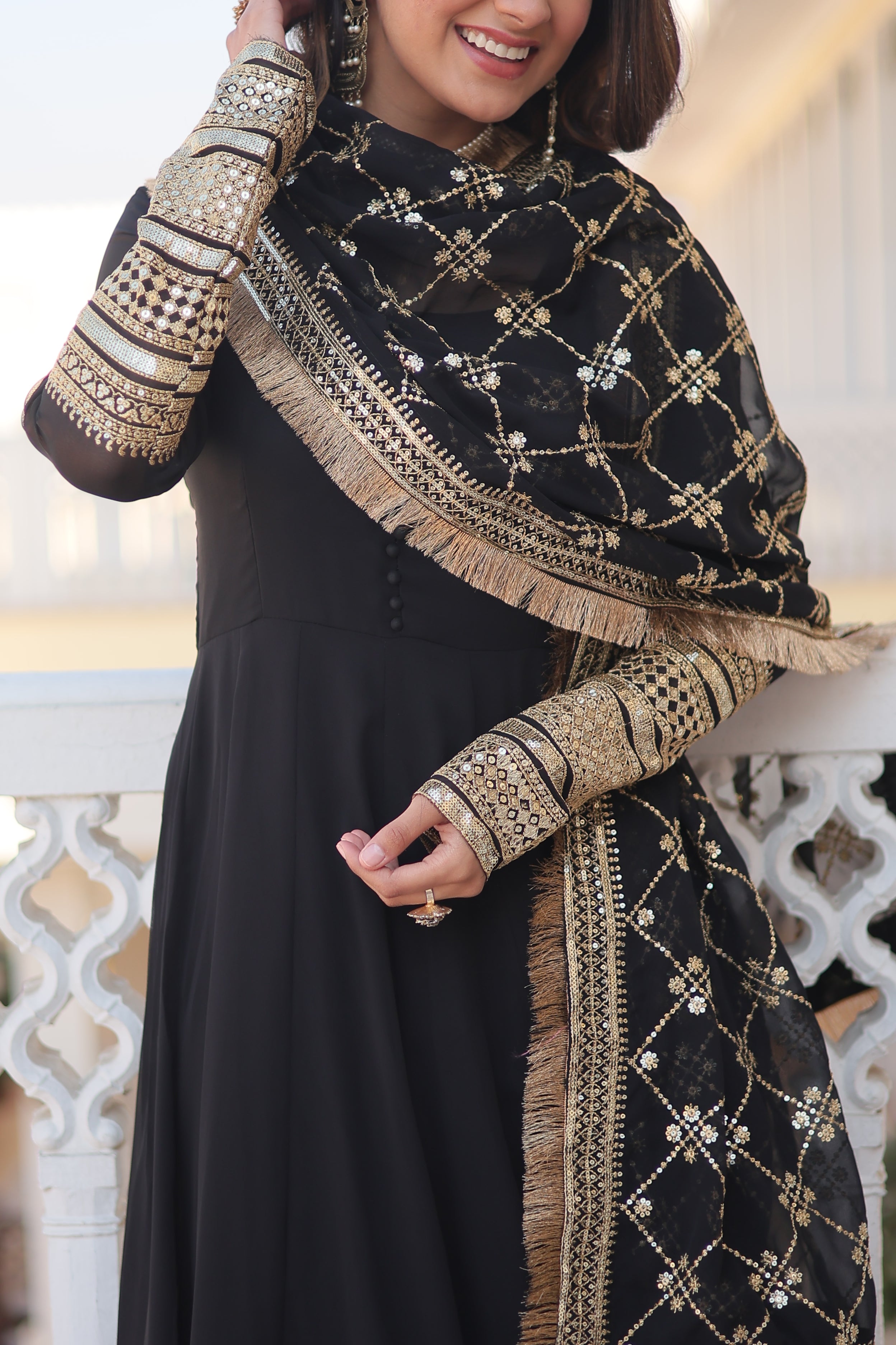 Person wearing a black and gold embroidered traditional outfit with a blurred background