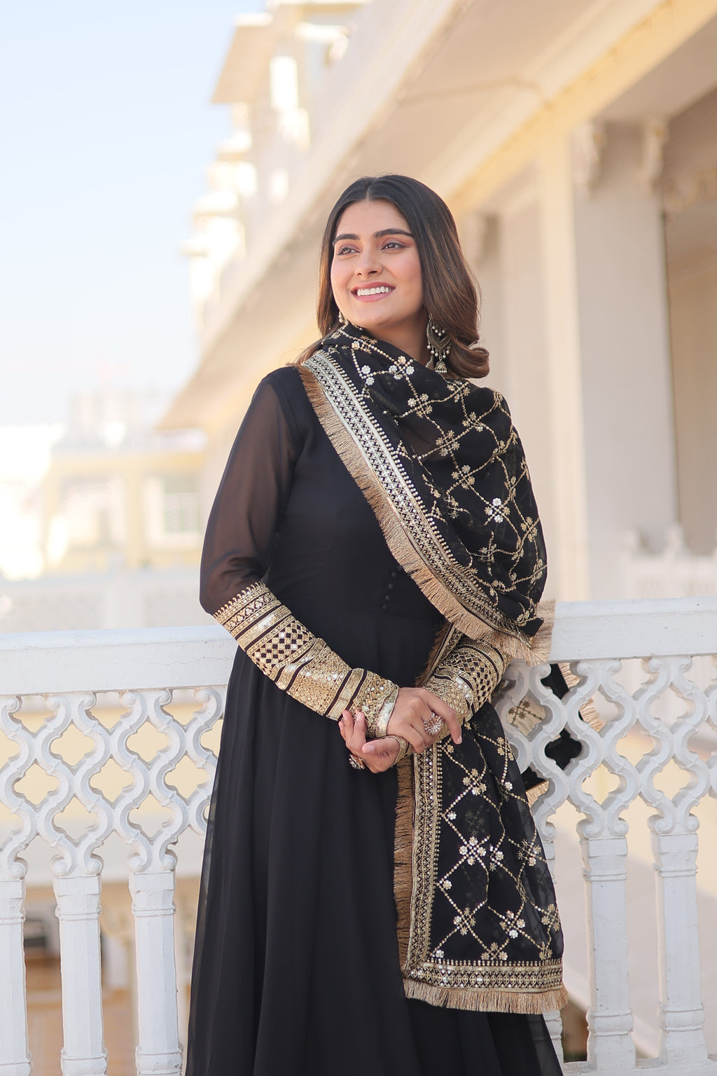 Woman in a black and gold traditional outfit standing on a staircase.