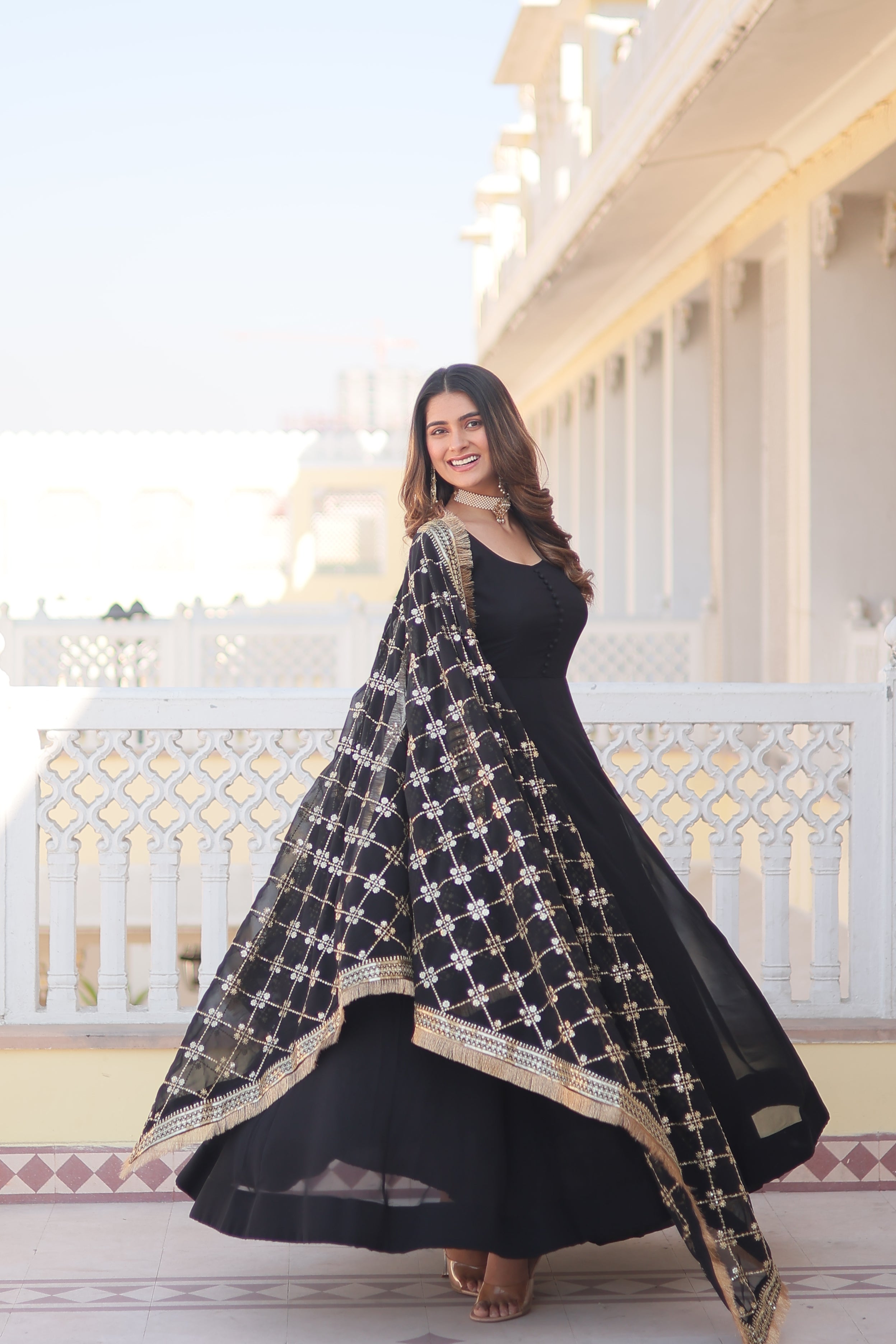 Woman in a black and gold traditional outfit standing on a staircase.