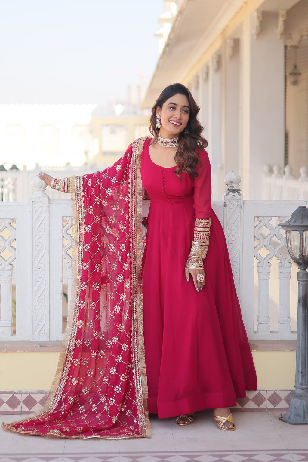 Woman in a red traditional outfit with a matching dupatta standing on a staircase.