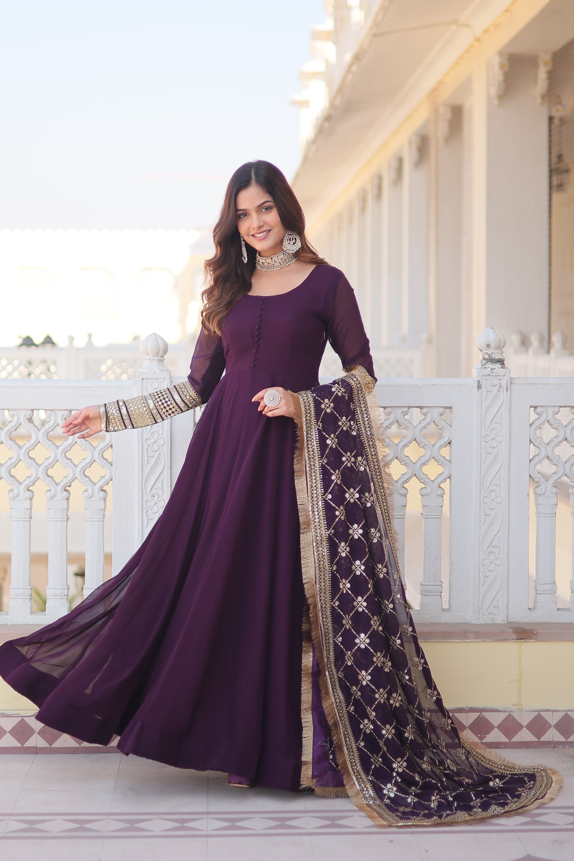 Woman in a purple traditional outfit with a long skirt standing on a staircase.