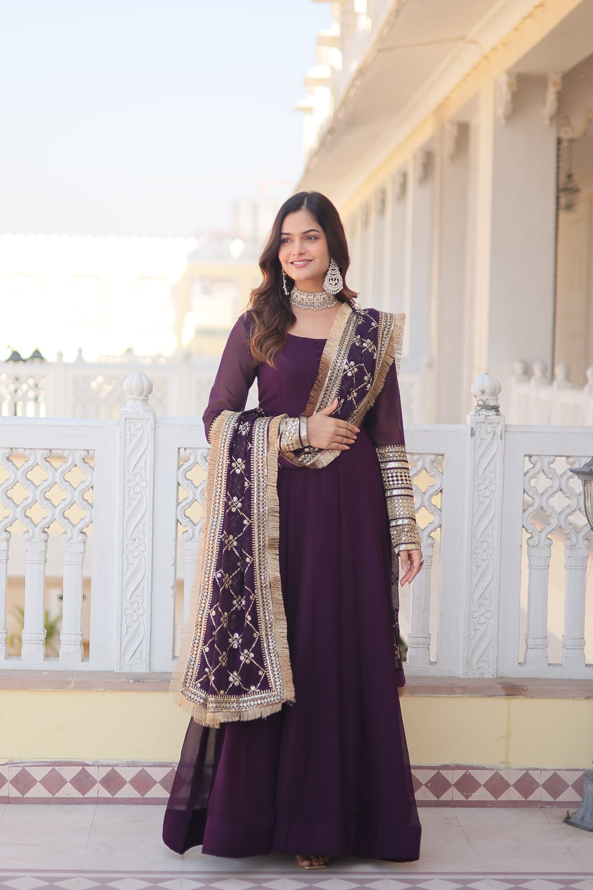 Woman in a purple dress with white patterns standing on a staircase.