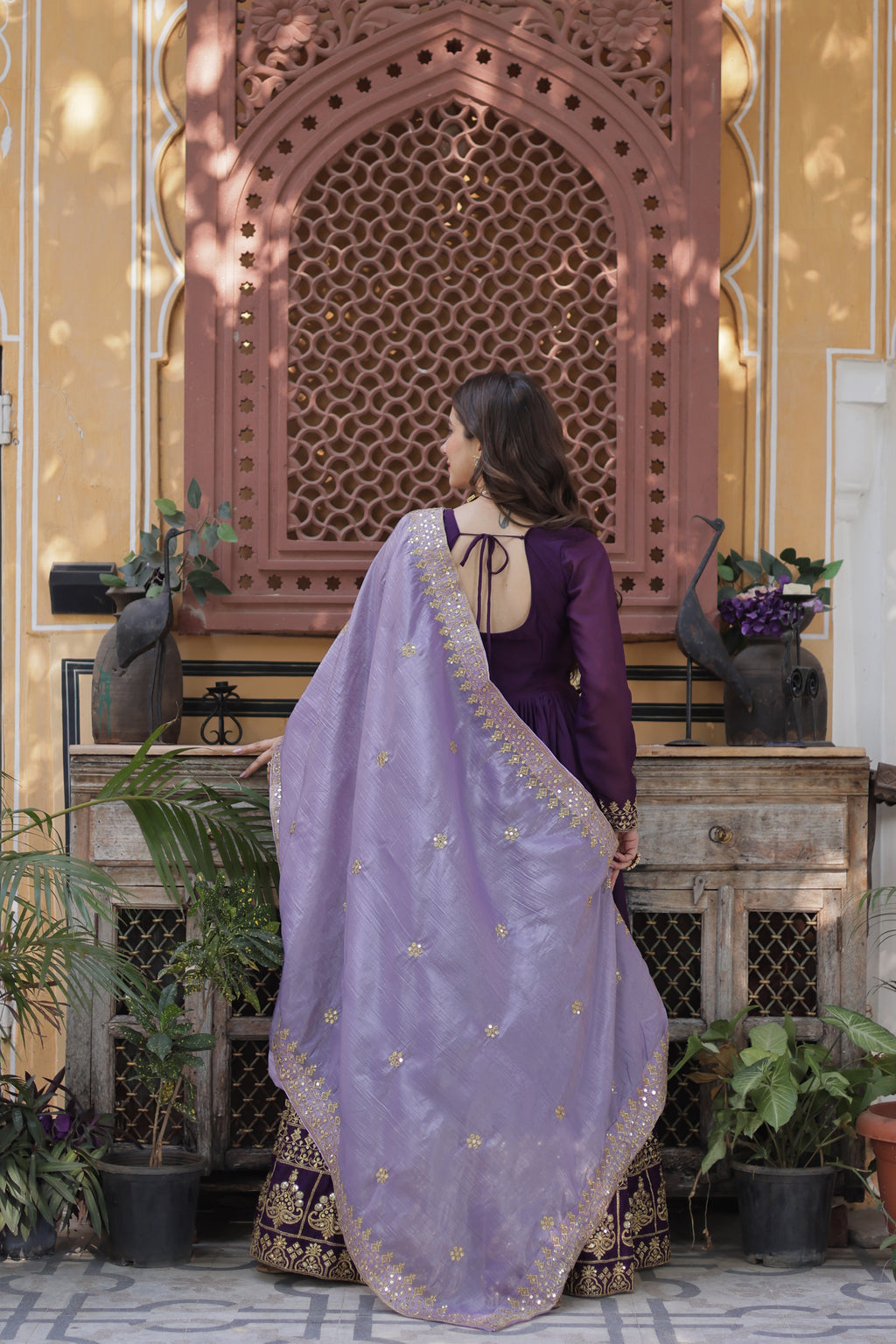 Person wearing a purple traditional outfit with a matching dupatta in an outdoor setting.