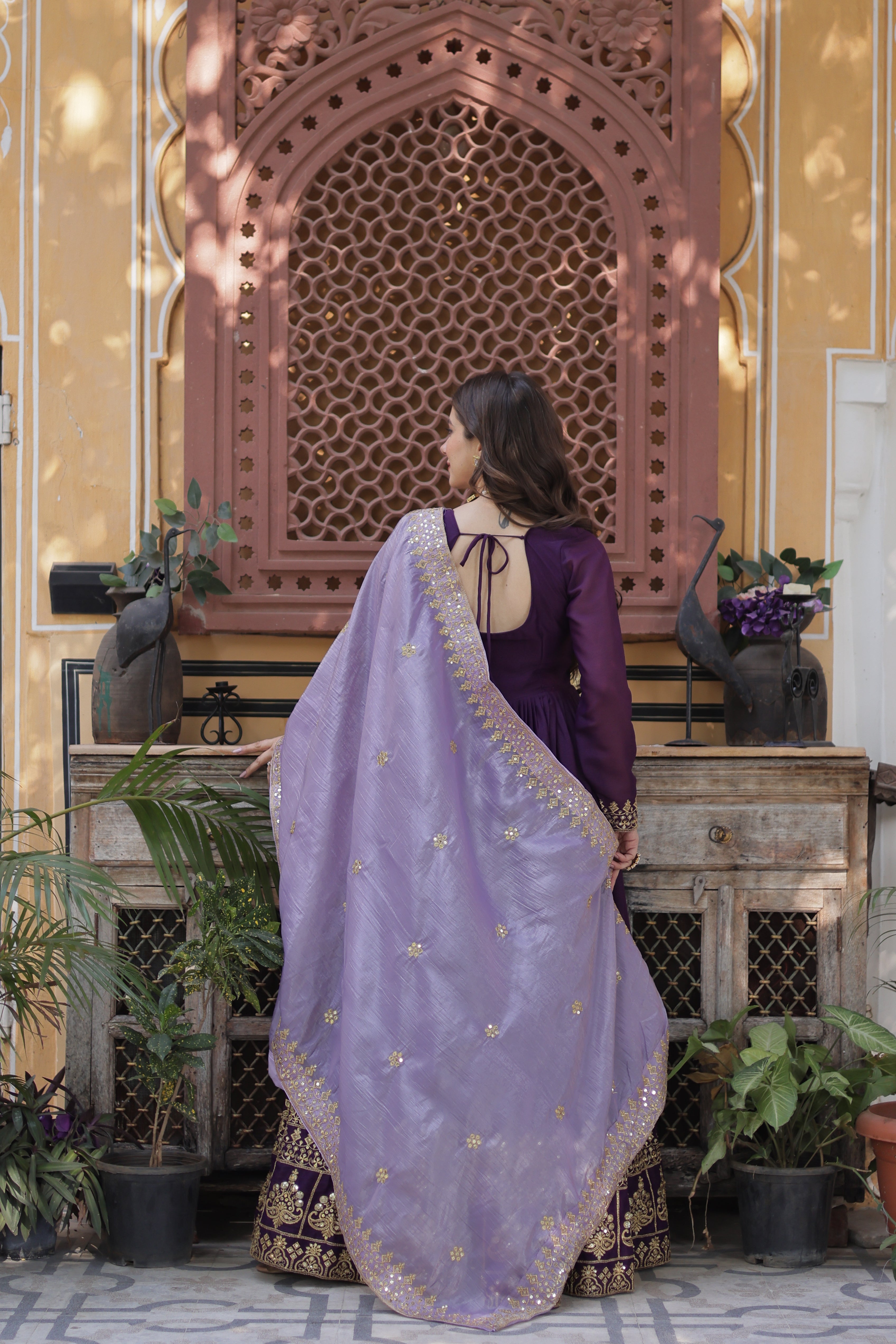 Person wearing a purple traditional outfit with a matching dupatta in an outdoor setting.