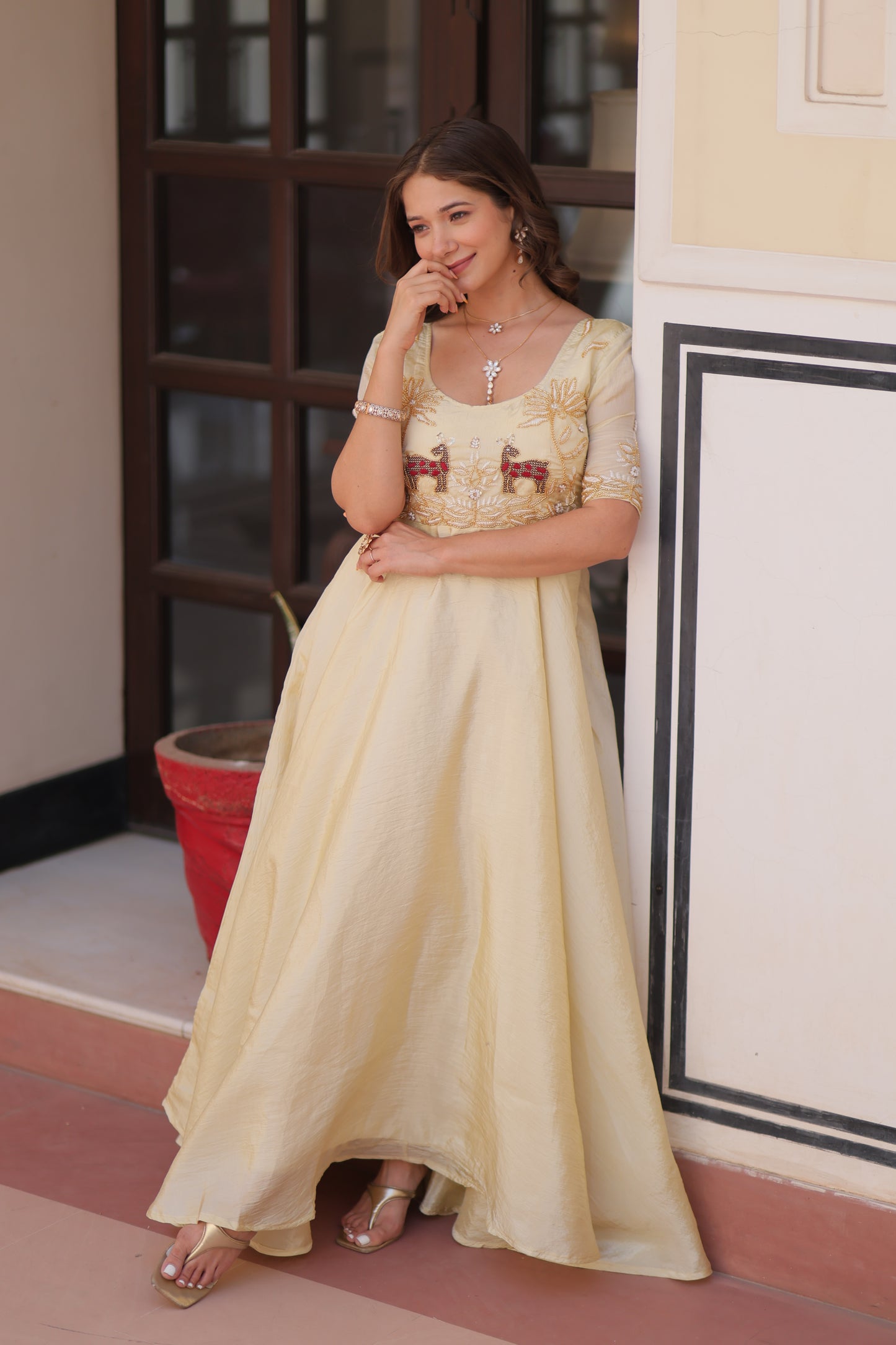 Woman in a long, light-colored dress standing indoors with a blurred background