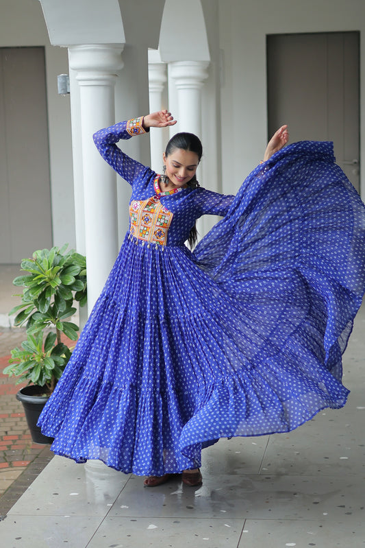 women in a blue traditional outfit with a colorful top, standing in an outdoor setting.
