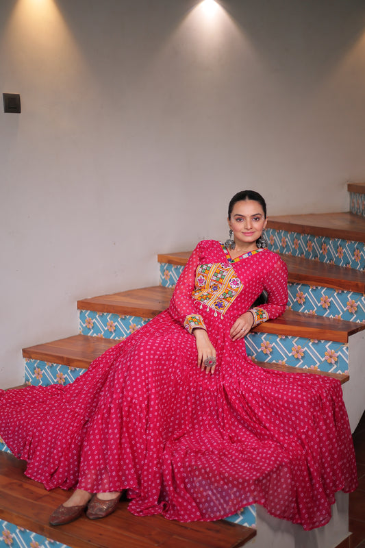 Person wearing a bright pink saree with a patterned blouse in a room.