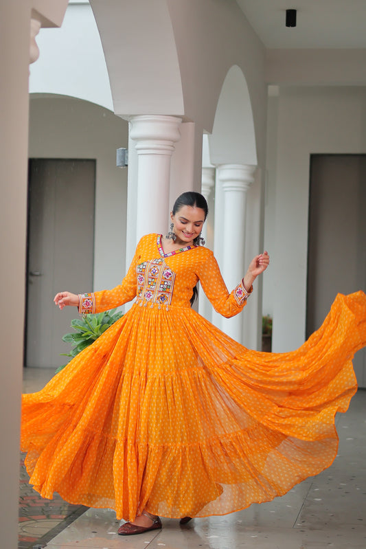 women in an orange traditional outfit with a long skirt, standing indoors.