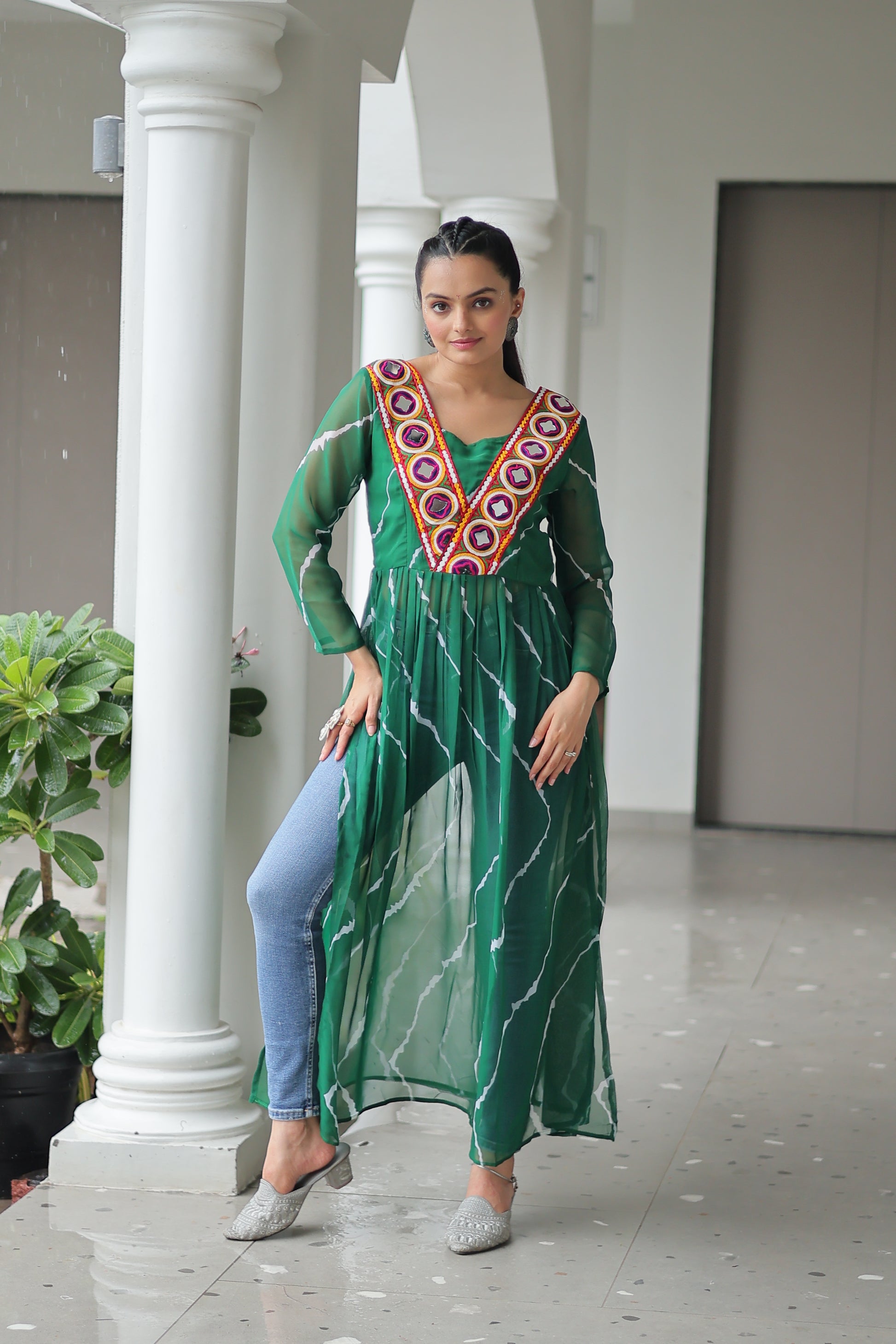 Woman wearing a green dress with a colorful pattern standing in front of a white column.