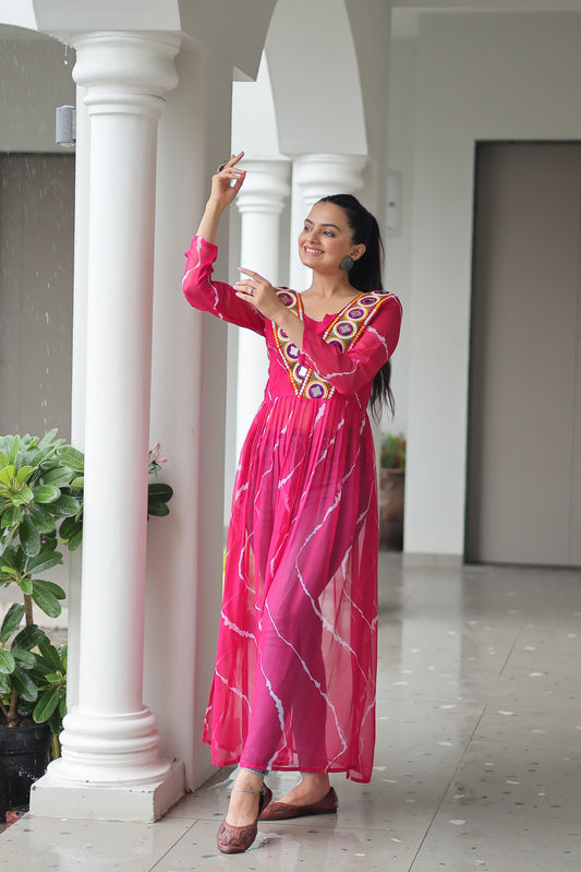 Woman in a pink dress standing between white columns with greenery in the background