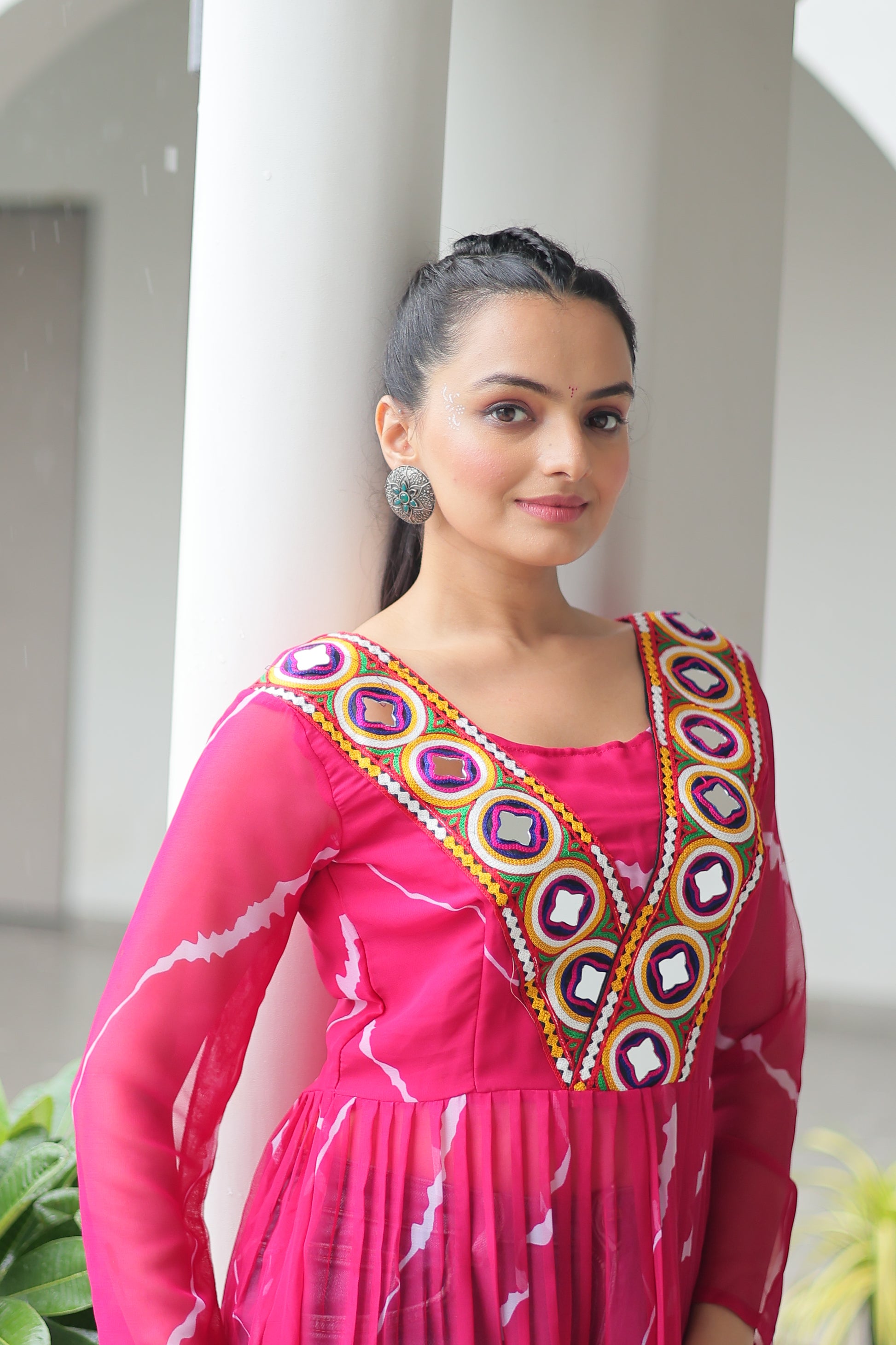 Woman in a pink traditional outfit with colorful embroidery on a white background