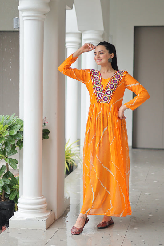 Woman in an orange dress with white patterns standing indoors.