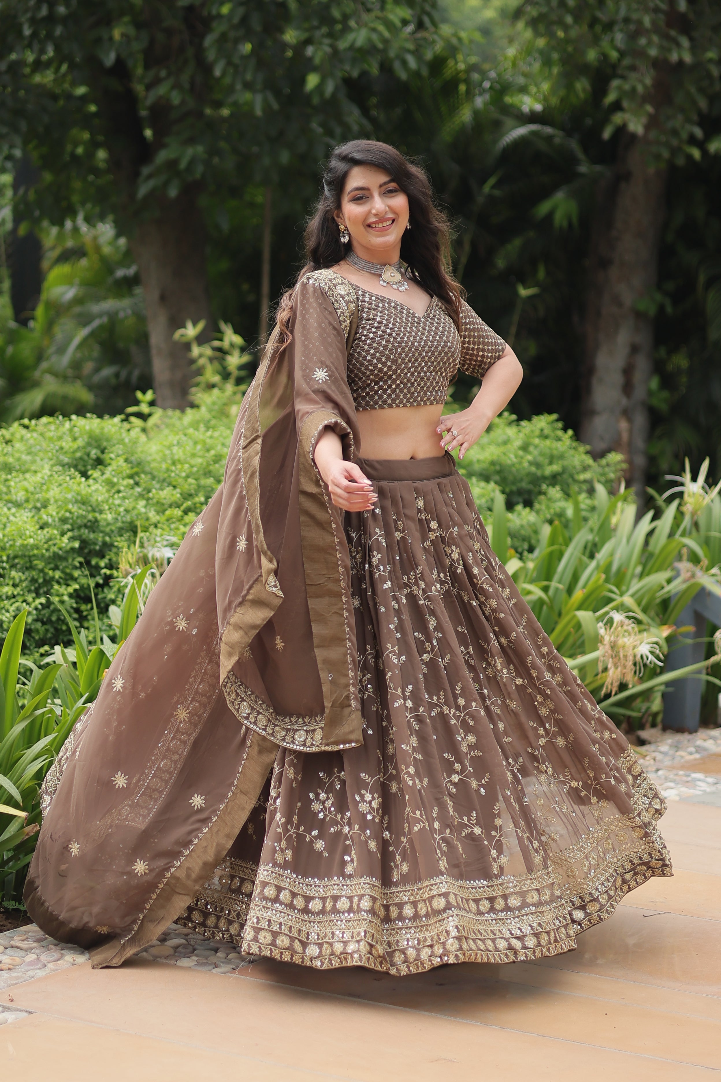 Woman in a traditional outfit with intricate designs standing outdoors.
