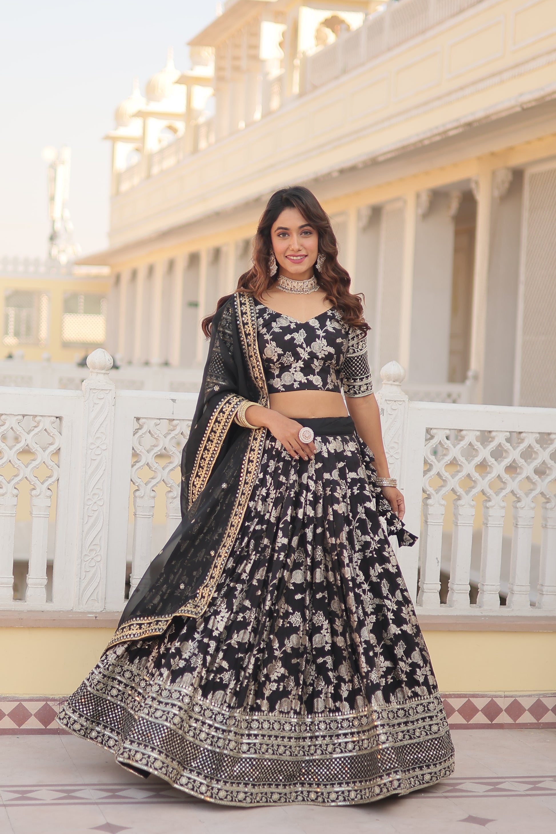 Woman in a black and white patterned traditional outfit standing in front of a white lattice background.
