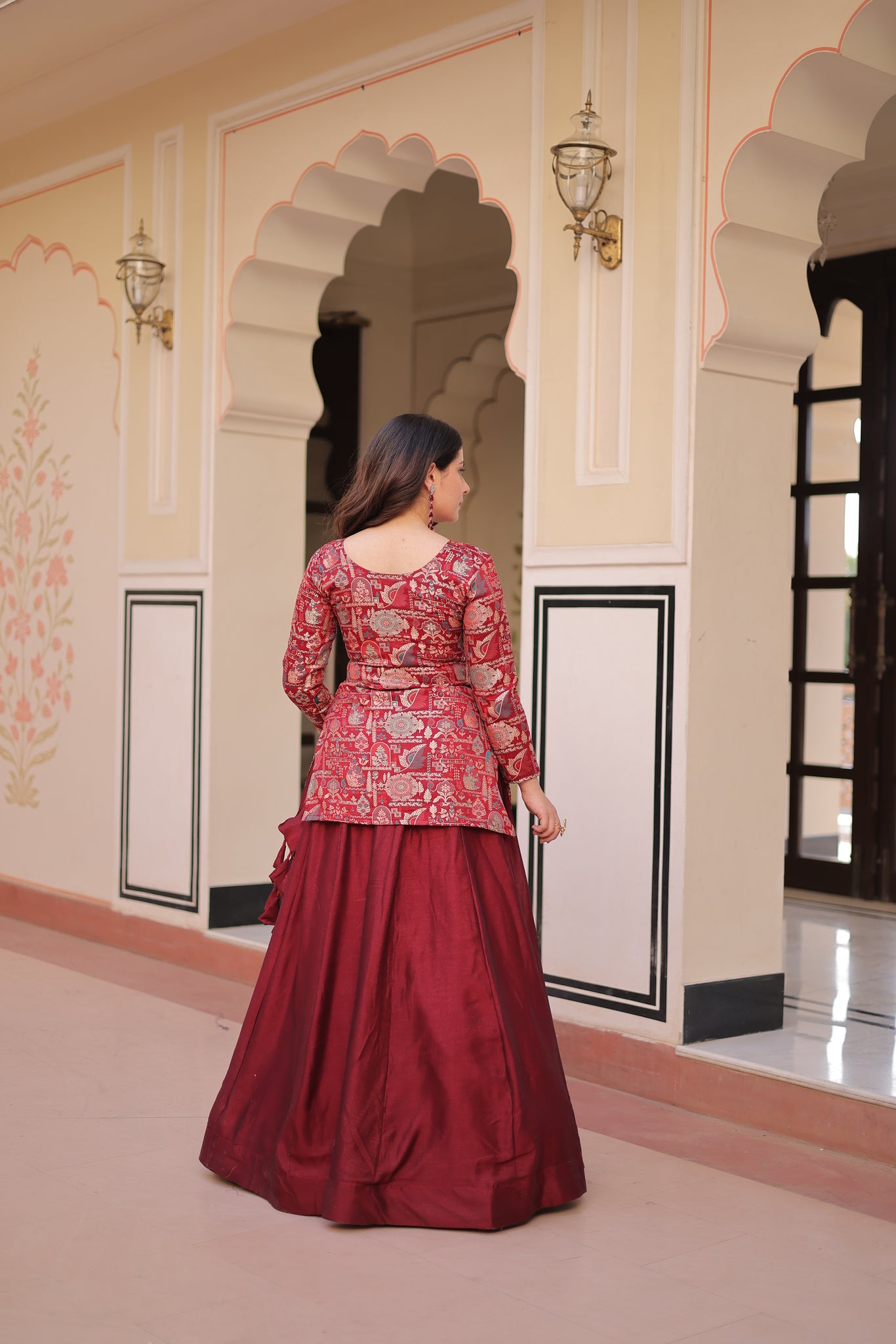 Woman wearing a red dress with floral pattern standing in front of a mirror.