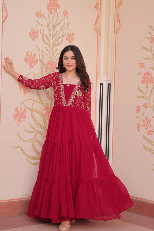 Woman wearing a red dress with floral patterns on a decorative wall.