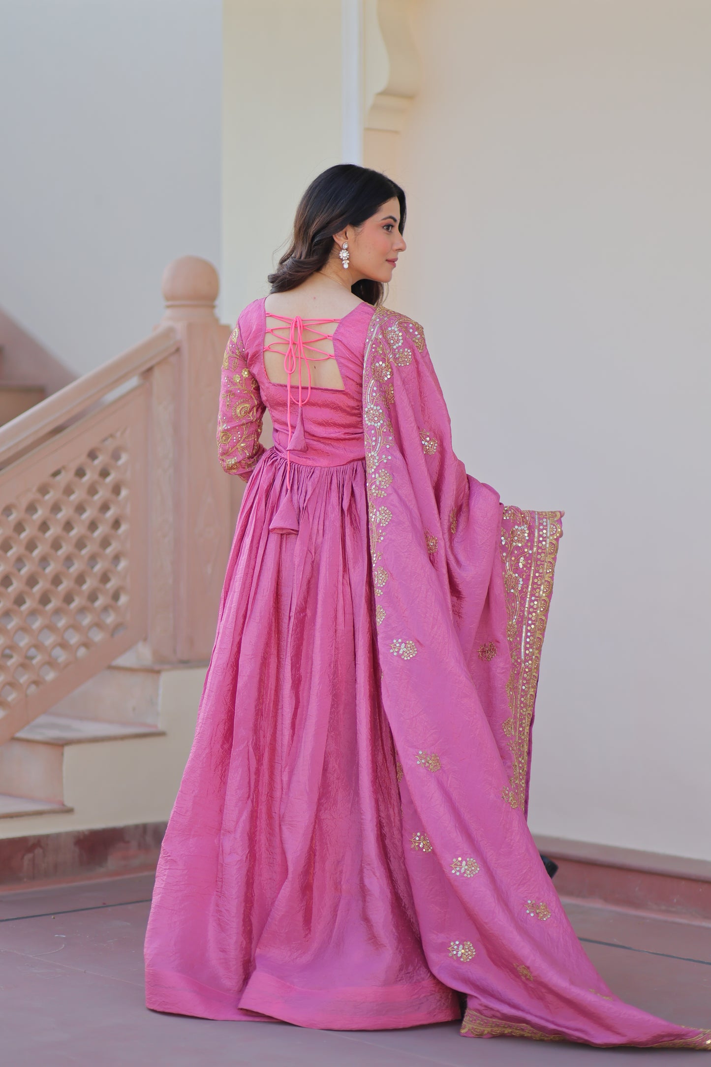 Pink traditional outfit with gold details on a mannequin against a neutral background
