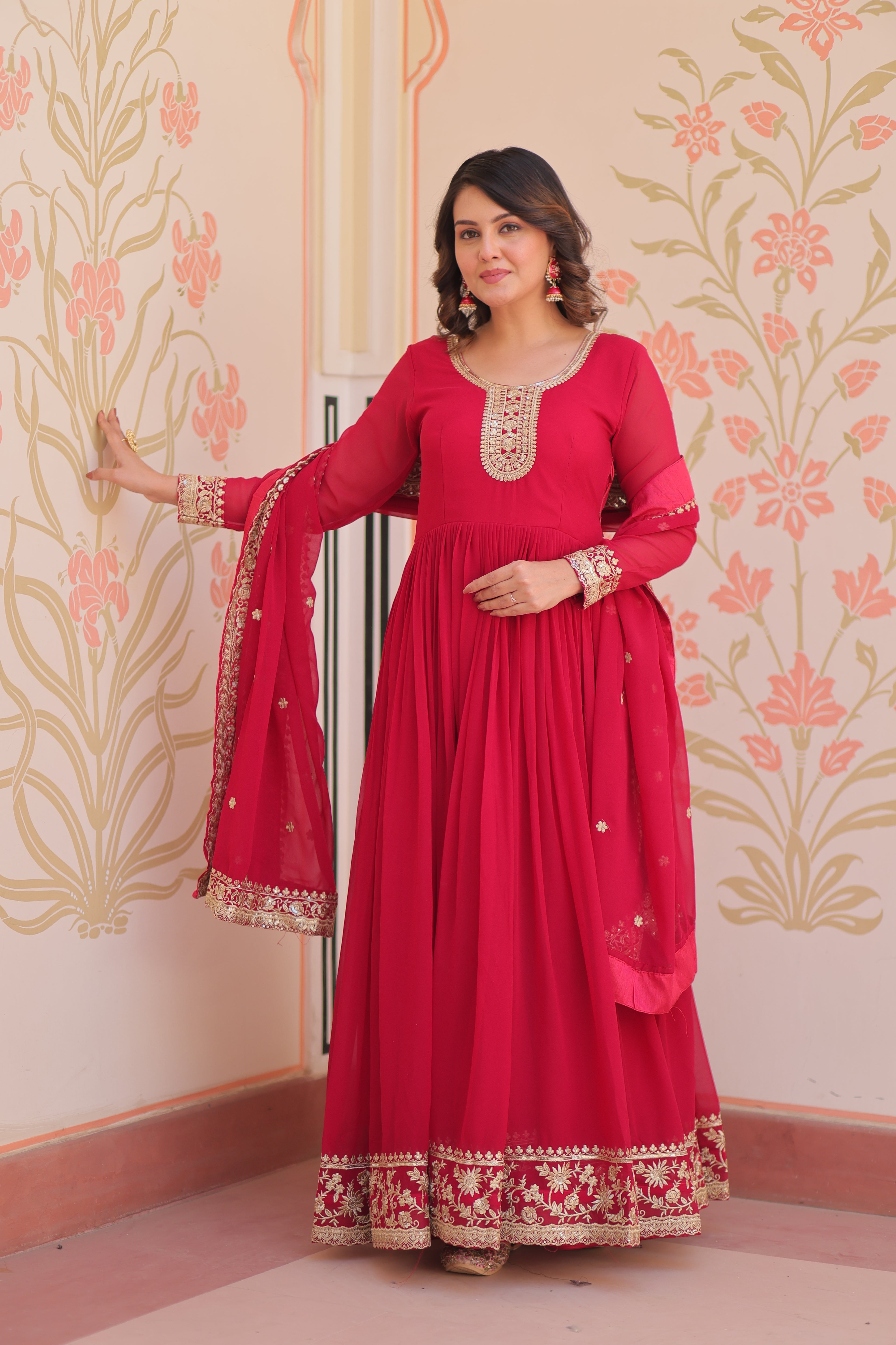 Woman in a red traditional outfit with floral wall pattern