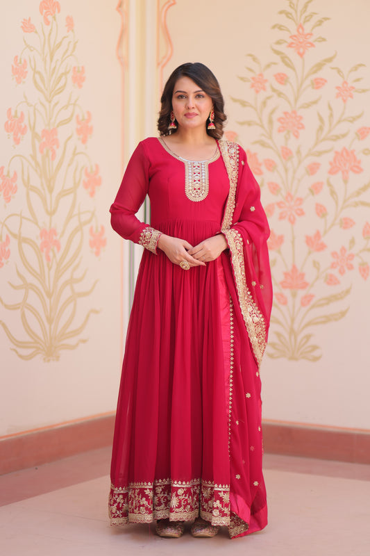 Woman wearing a red traditional outfit with gold details against a floral patterned wall.