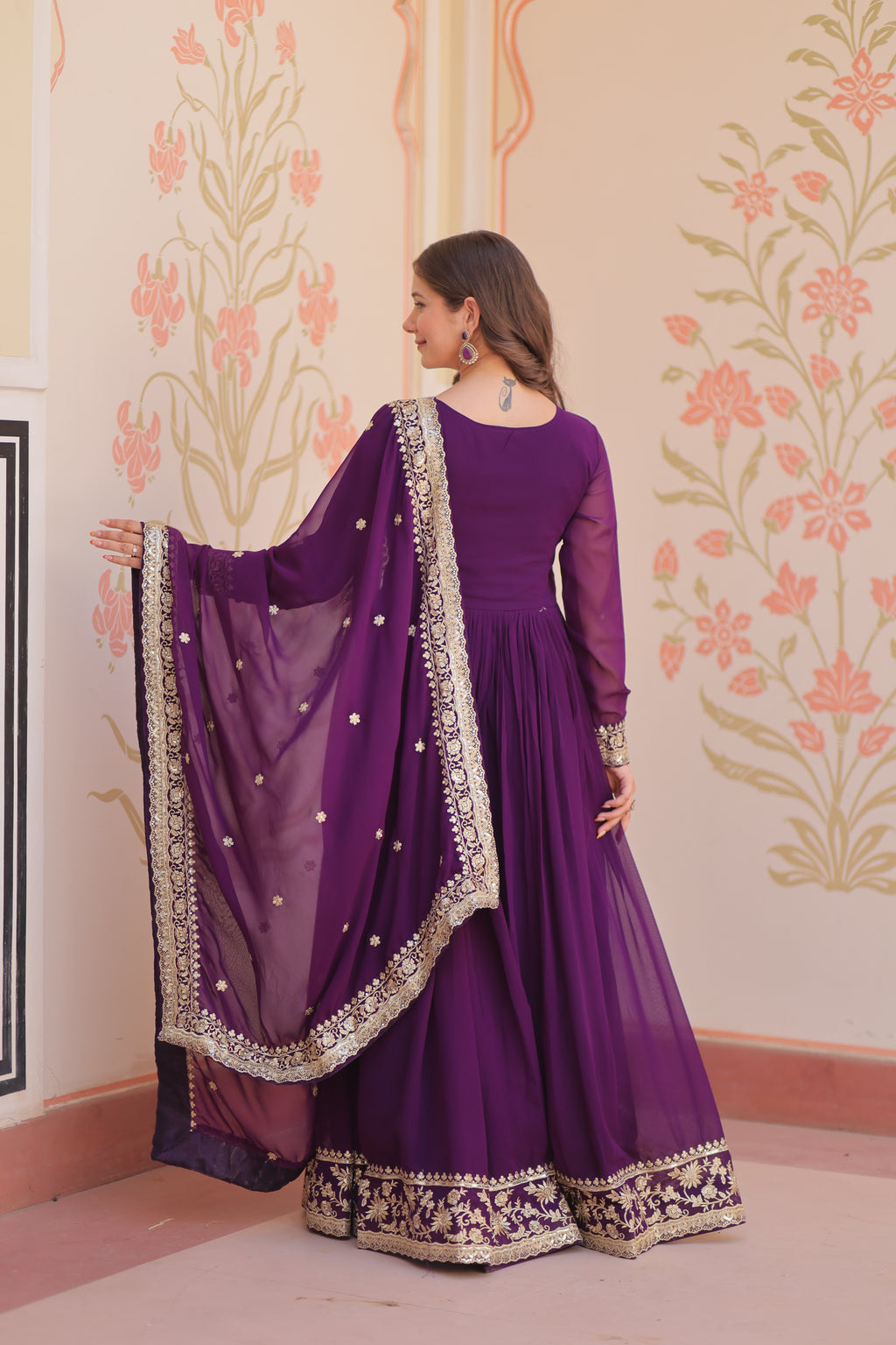 Purple traditional outfit with intricate designs on a floral patterned floor.