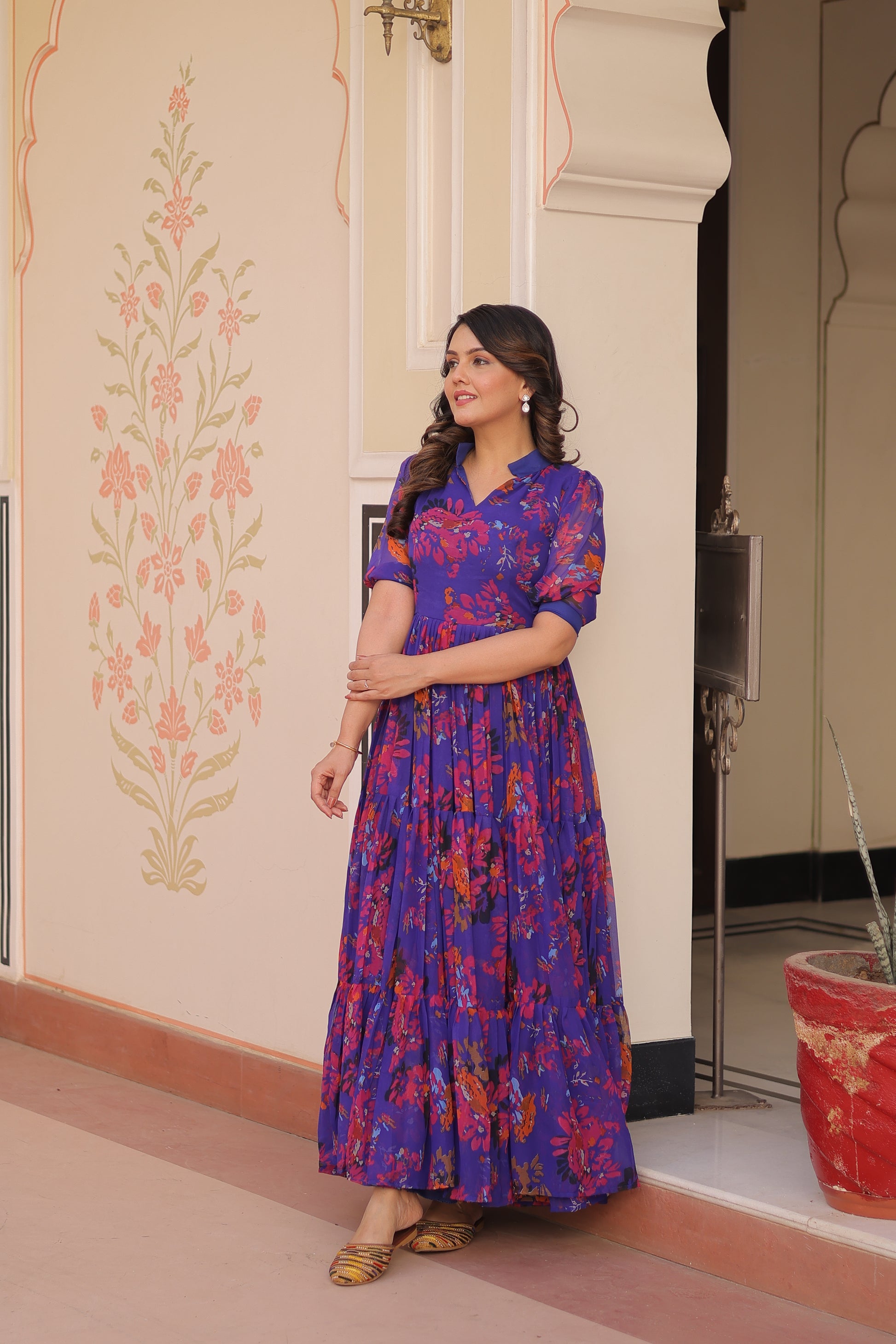 Woman wearing a blue floral dress standing in front of a mirror.