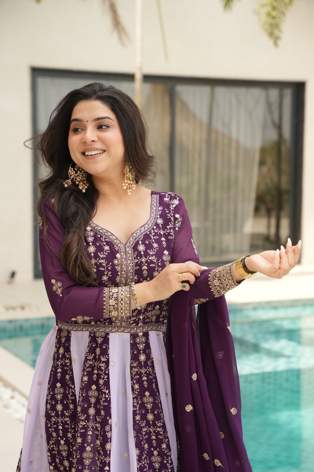 Woman wearing a purple traditional outfit with gold embroidery indoors.