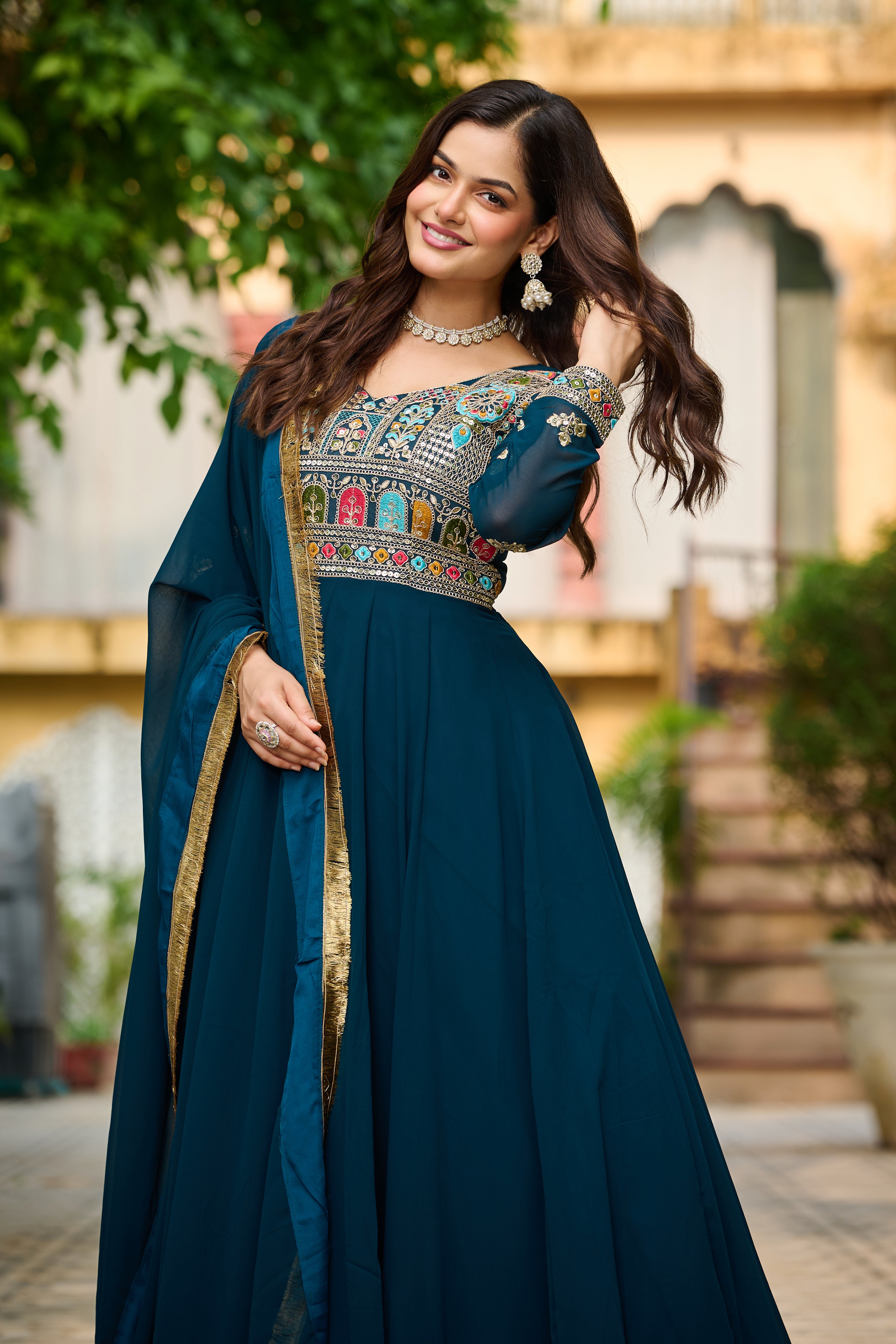 Woman in a traditional blue outfit with intricate designs, standing outdoors.