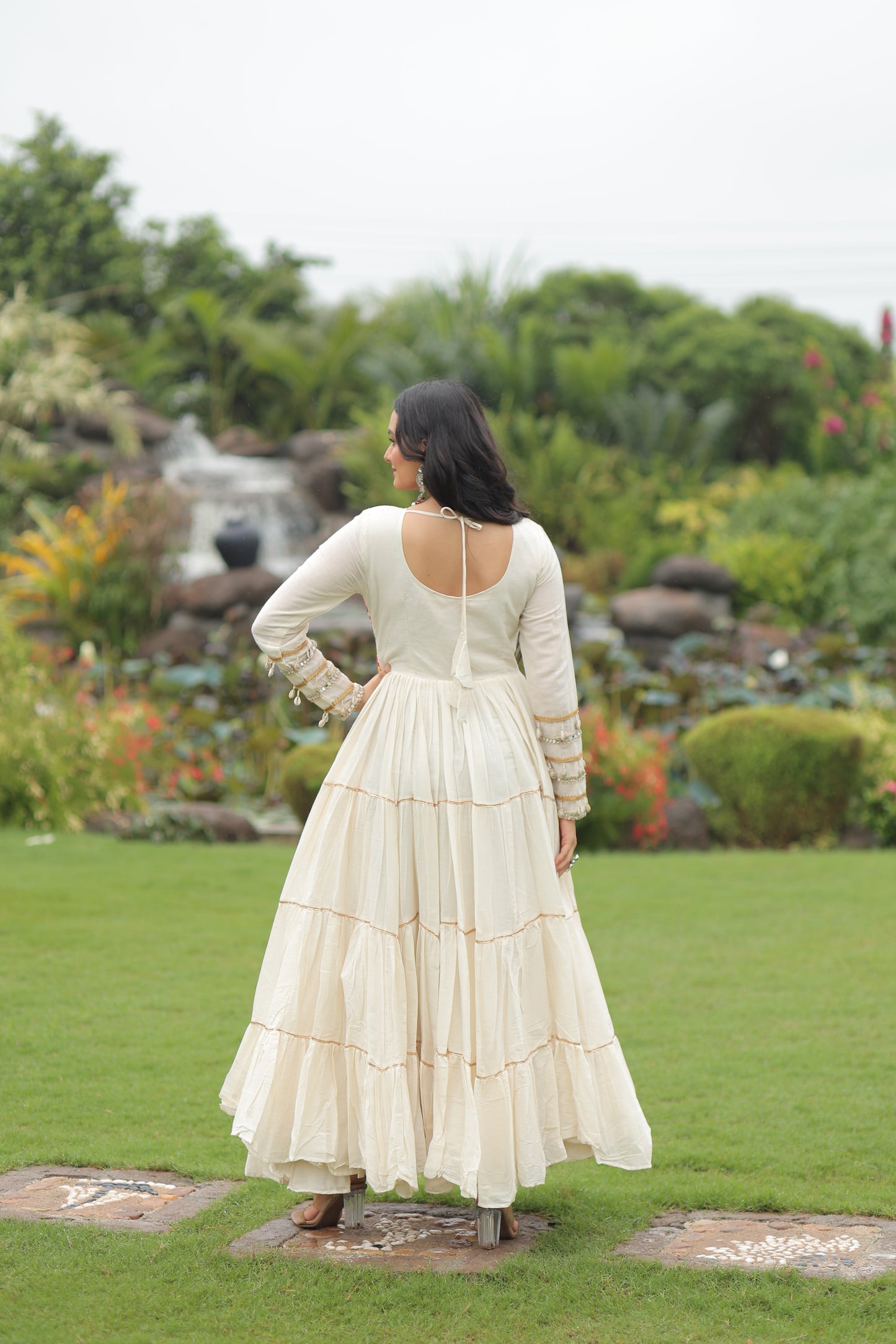 Woman in a white dress standing in a garden with green grass and blurred background