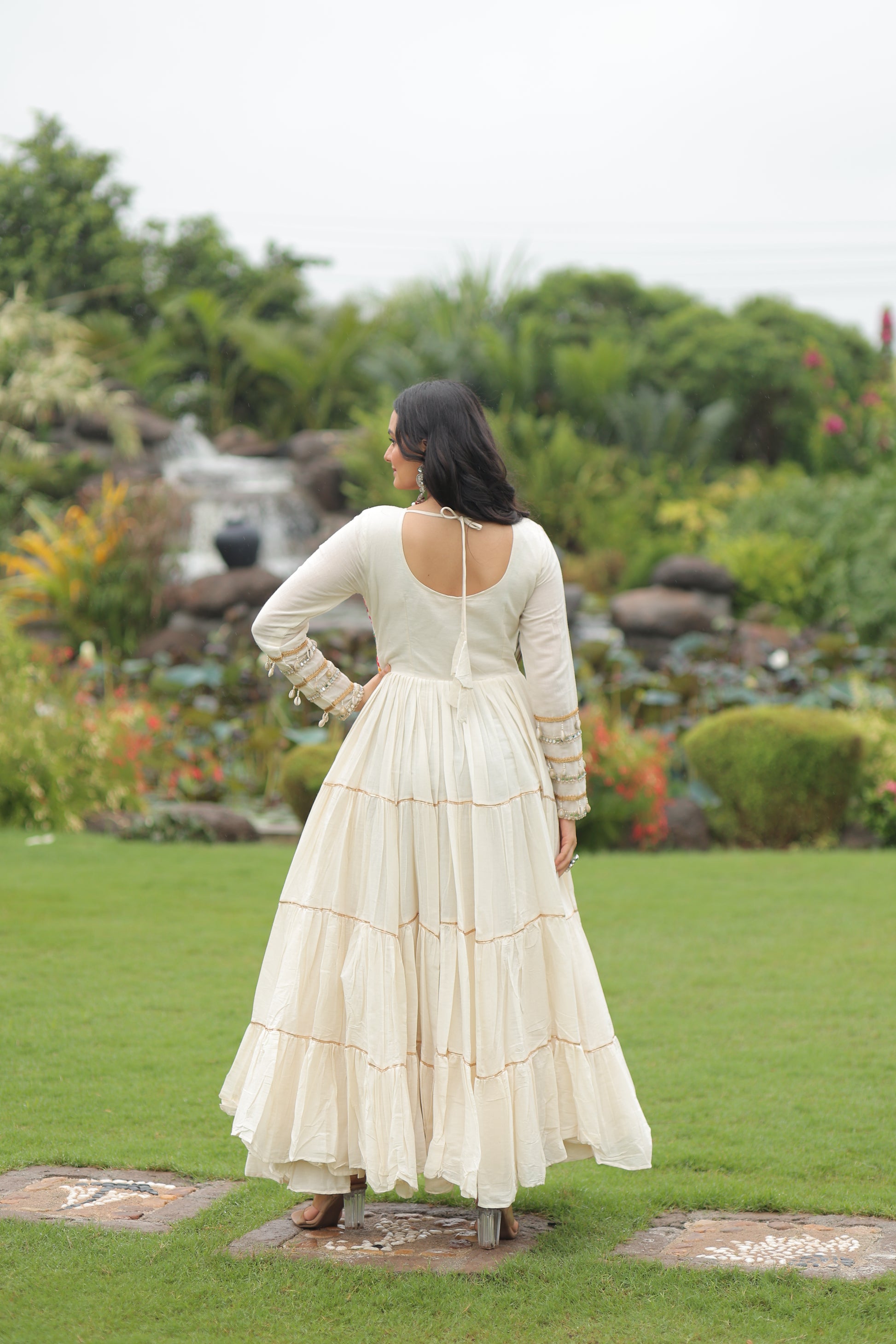 Woman in a white dress standing in a garden with green grass and blurred background