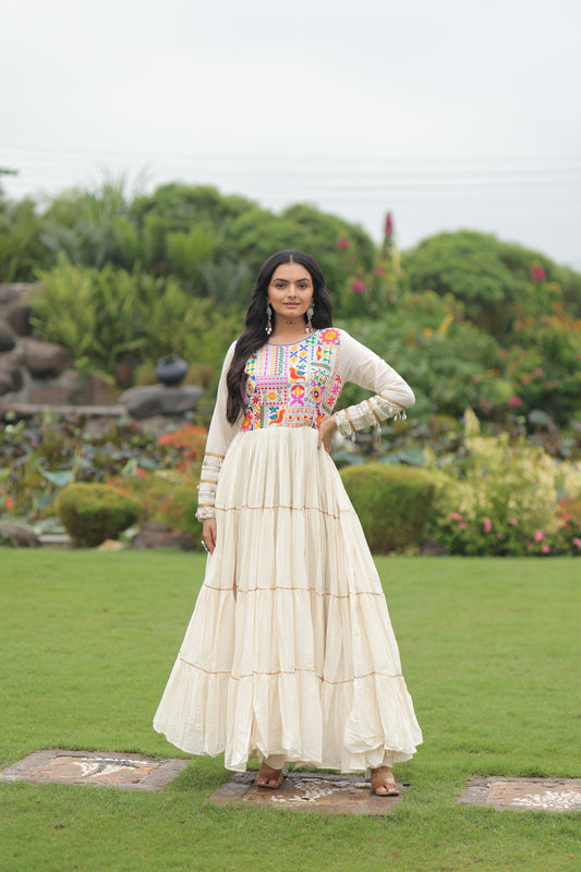 Woman in a colorful dress standing in a garden with greenery and a pond in the background