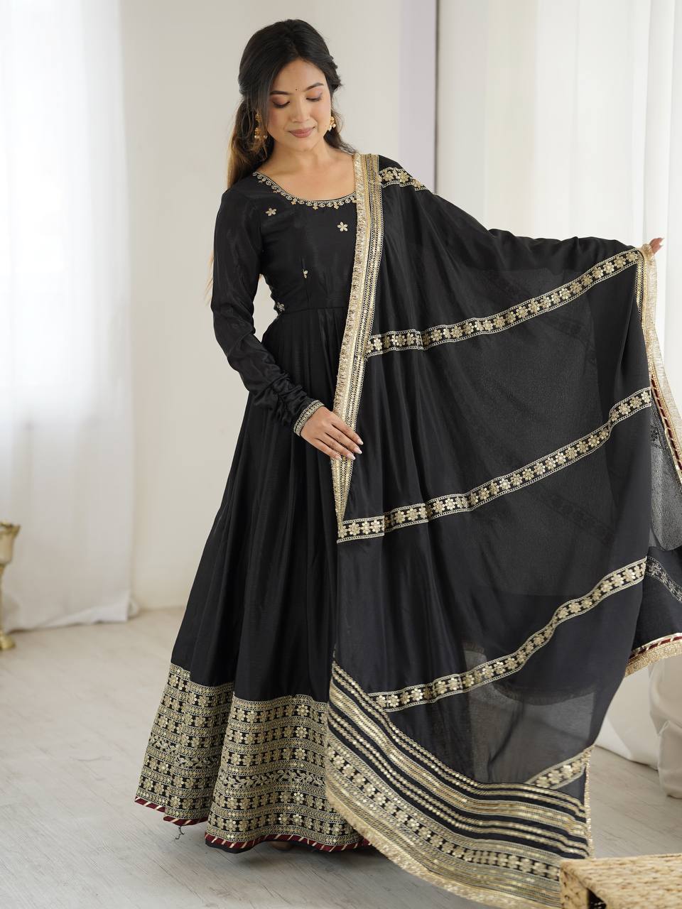 Woman wearing a black traditional outfit with a sheer dupatta in a minimalistic setting