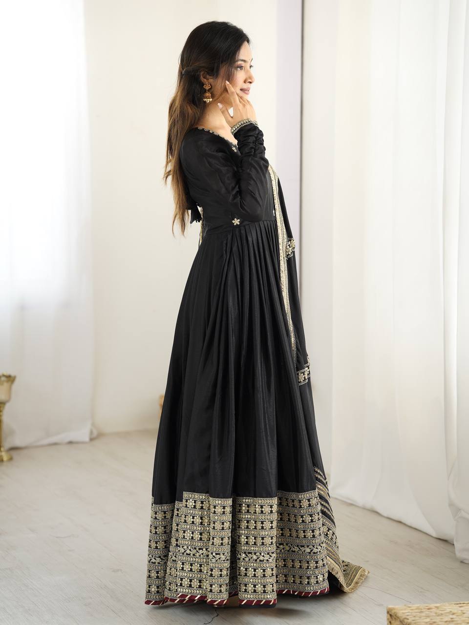 Woman wearing a black anarkali suit with intricate embroidery in a minimalistic setting